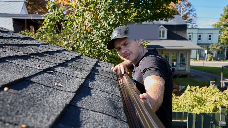 Technician clearing leaves and debris from a gutter